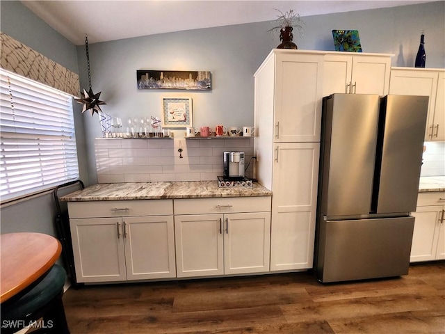 kitchen with dark wood-type flooring, white cabinetry, freestanding refrigerator, and light stone countertops