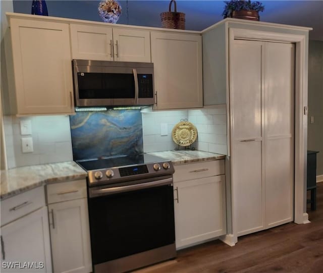 kitchen featuring backsplash, dark hardwood / wood-style floors, light stone countertops, white cabinetry, and stainless steel appliances