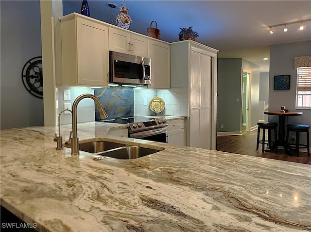 kitchen with dark hardwood / wood-style flooring, backsplash, light stone counters, sink, and white cabinets