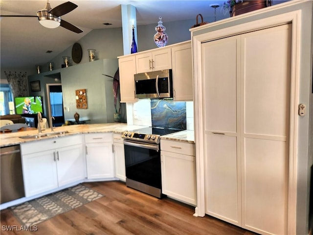 kitchen featuring stainless steel appliances, white cabinets, a sink, and a peninsula