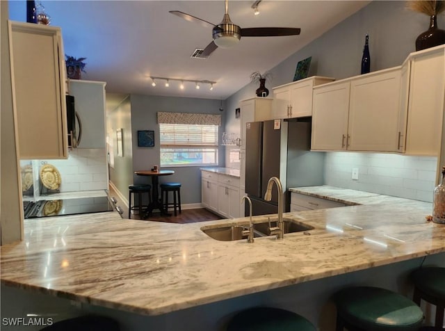 kitchen featuring a peninsula, black appliances, vaulted ceiling, and a sink