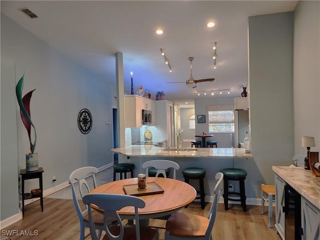 dining area with light wood-style floors, baseboards, visible vents, and track lighting