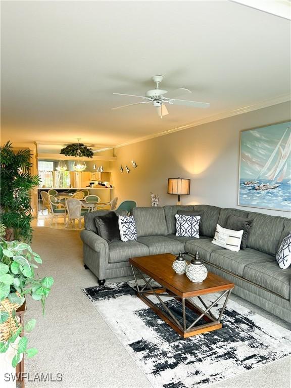 carpeted living room featuring ceiling fan and ornamental molding