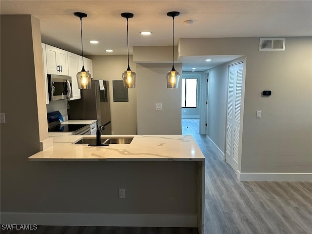 kitchen featuring light wood-type flooring, white cabinets, stainless steel appliances, light stone countertops, and pendant lighting