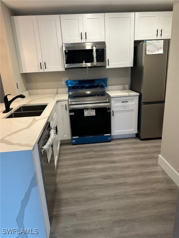 kitchen with sink, white cabinetry, light wood-type flooring, and stainless steel appliances