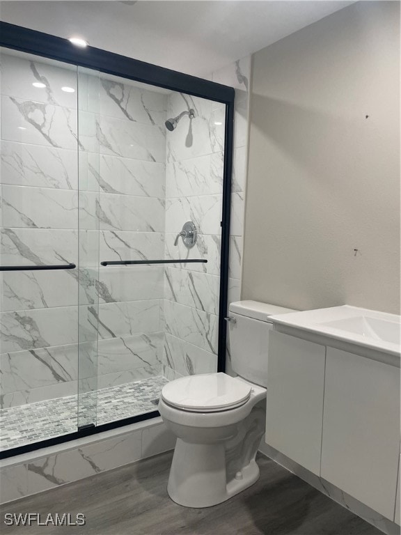 bathroom with vanity, a shower with door, hardwood / wood-style flooring, and toilet