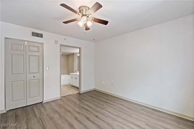 unfurnished bedroom with a closet, ensuite bath, ceiling fan, and light wood-type flooring