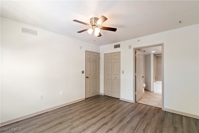 unfurnished bedroom featuring hardwood / wood-style flooring, ensuite bath, and ceiling fan