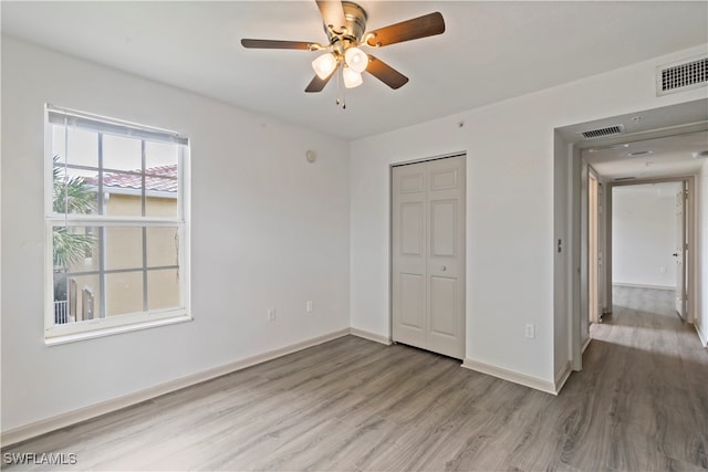 unfurnished bedroom featuring ceiling fan, wood-type flooring, and a closet