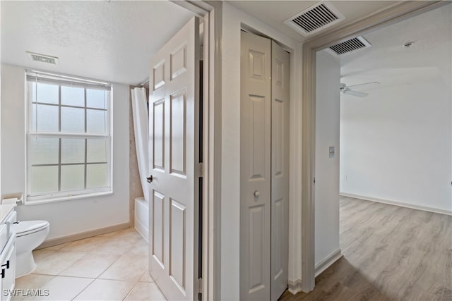 full bathroom featuring hardwood / wood-style flooring, shower / bath combination with curtain, toilet, vanity, and ceiling fan