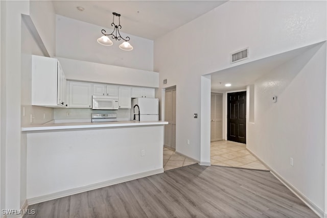 kitchen with white cabinetry, light hardwood / wood-style floors, decorative light fixtures, and white appliances