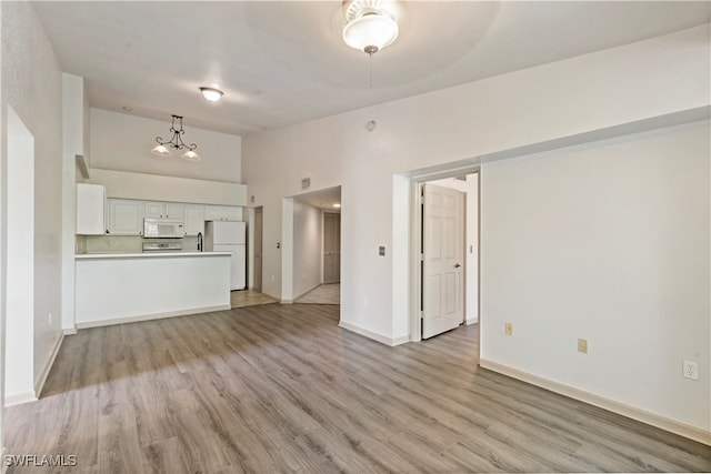 unfurnished living room with light hardwood / wood-style floors and a towering ceiling