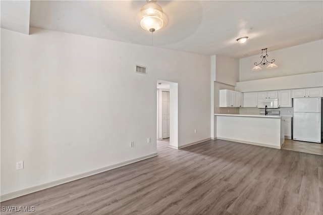 unfurnished living room with a towering ceiling, hardwood / wood-style floors, and sink