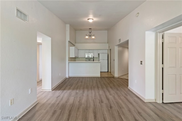 interior space with an inviting chandelier, a high ceiling, and light hardwood / wood-style flooring