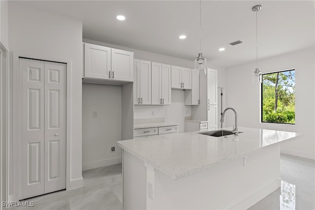 kitchen with sink, white cabinets, a kitchen island with sink, and light tile patterned floors