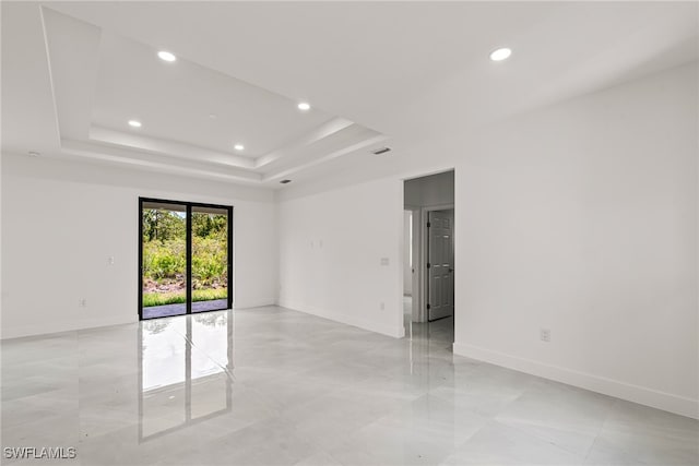 tiled spare room with a raised ceiling