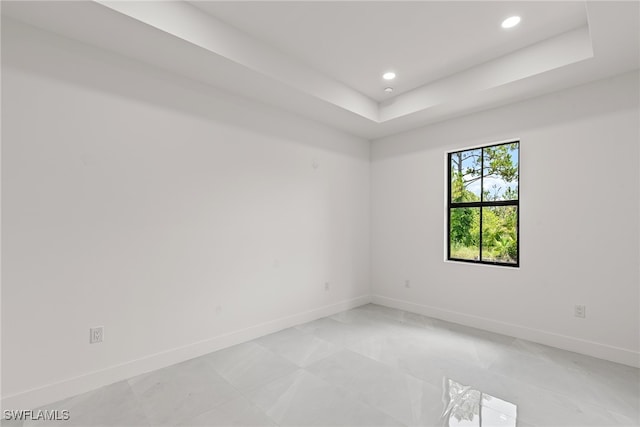 tiled spare room featuring a tray ceiling