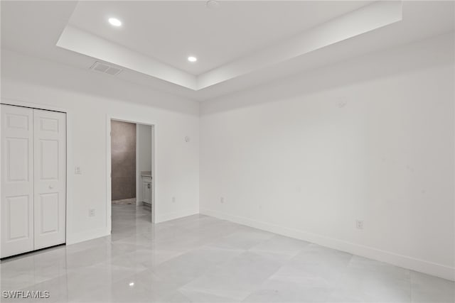 unfurnished bedroom with a raised ceiling and light tile patterned floors