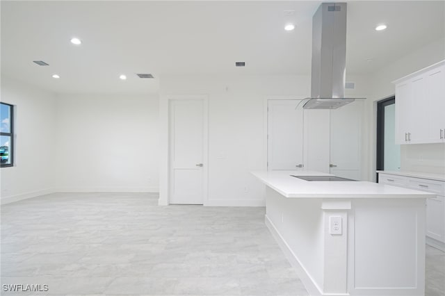 interior space featuring island exhaust hood, black electric stovetop, white cabinets, and a kitchen island