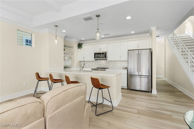 kitchen with white cabinetry, hanging light fixtures, stainless steel appliances, and sink