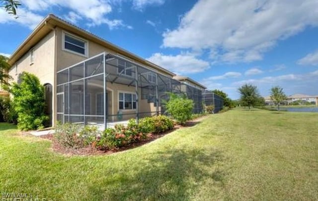 back of house featuring a lanai and a lawn