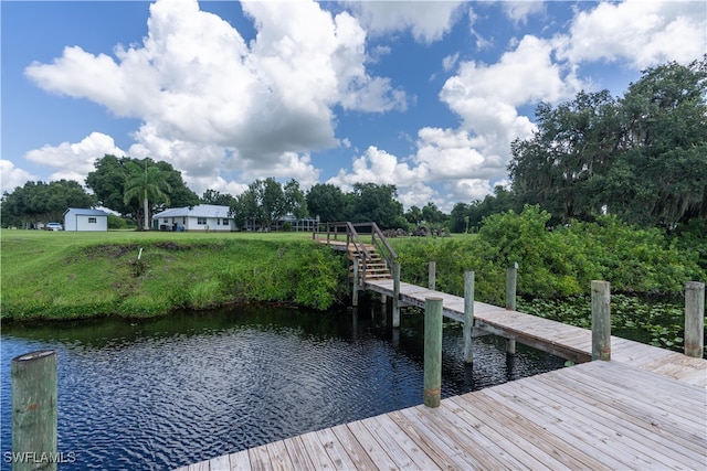 dock area with a water view and a lawn