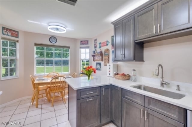 kitchen featuring sink, kitchen peninsula, dark brown cabinets, and light tile patterned floors