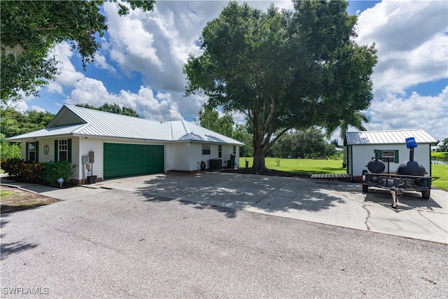 view of front of house with a garage, a front lawn, and central air condition unit