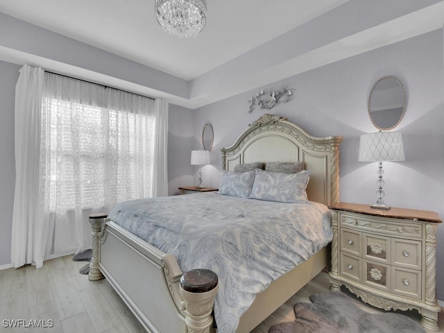 bedroom with light hardwood / wood-style floors and an inviting chandelier