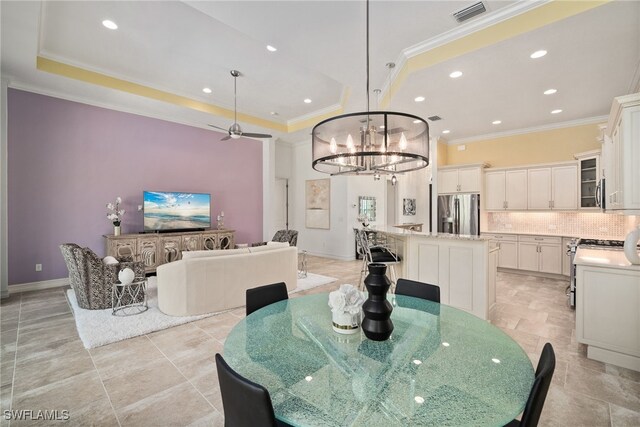 dining space featuring ornamental molding, a tray ceiling, and ceiling fan with notable chandelier