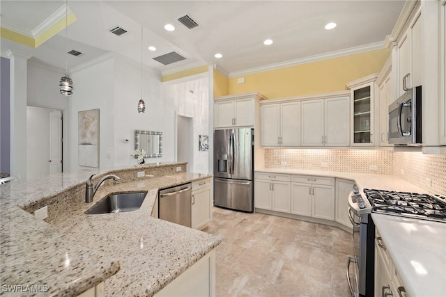 kitchen featuring light stone counters, ornamental molding, stainless steel appliances, decorative light fixtures, and sink