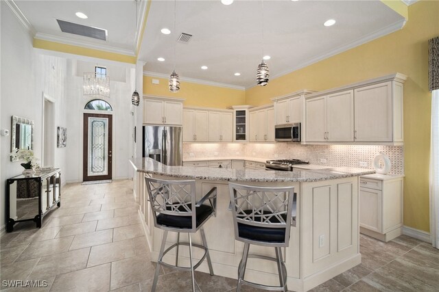 kitchen featuring appliances with stainless steel finishes, a breakfast bar, backsplash, a large island, and light stone countertops