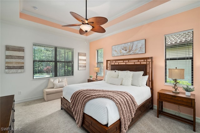 carpeted bedroom with ceiling fan, a raised ceiling, and ornamental molding