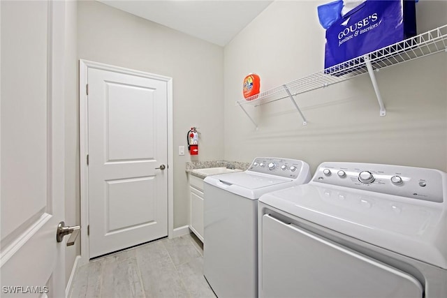 clothes washing area featuring baseboards, cabinet space, separate washer and dryer, a sink, and light wood-style floors