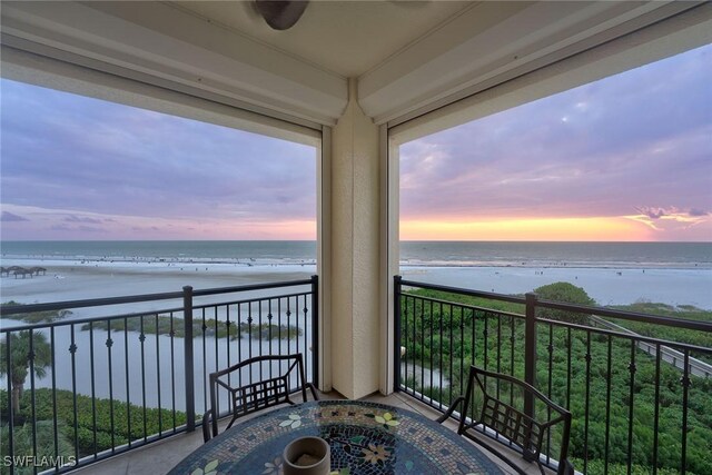 balcony at dusk featuring a water view