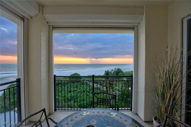 balcony at dusk featuring a water view