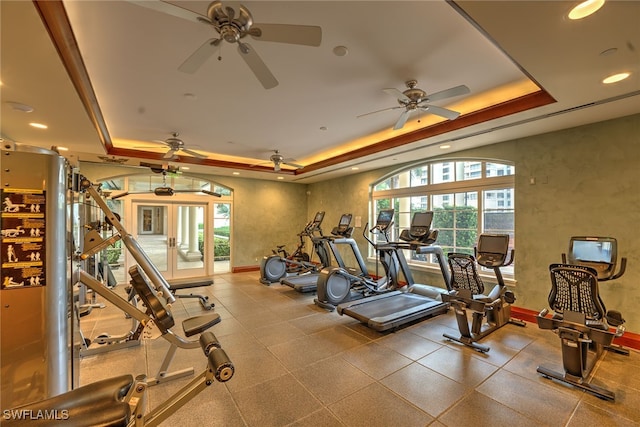 exercise room with ceiling fan and a raised ceiling