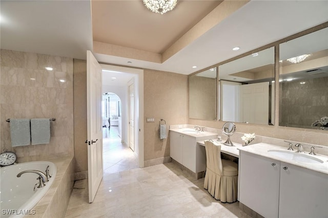 bathroom with double vanity, a tray ceiling, a sink, and a bath