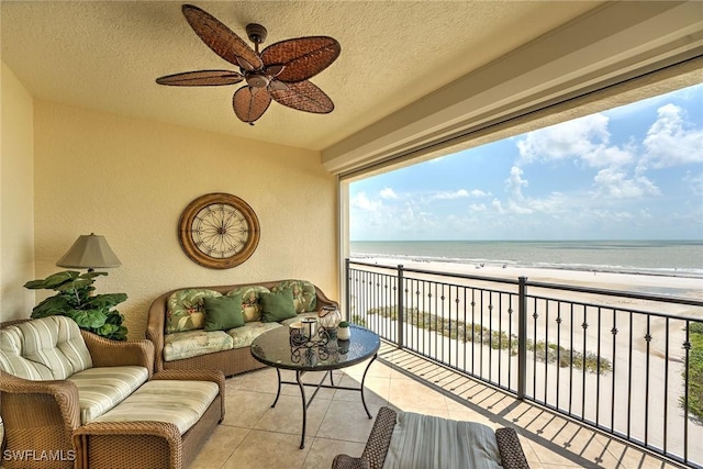 balcony featuring an outdoor living space, a water view, ceiling fan, and a beach view