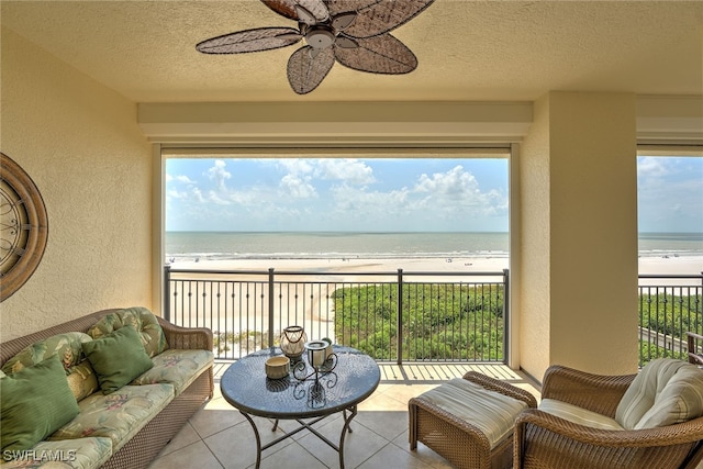 balcony featuring ceiling fan, a water view, and a beach view