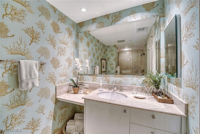 full bathroom featuring a stall shower, visible vents, vanity, and wallpapered walls