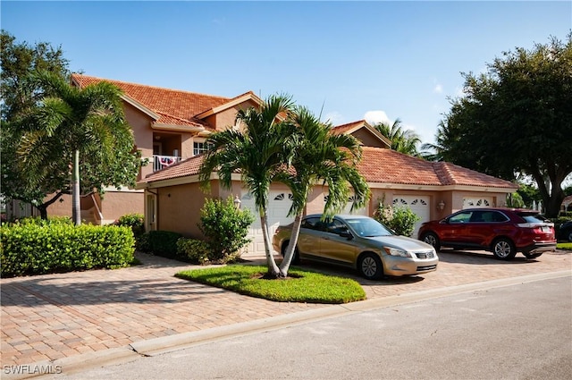 view of front of house with a garage, a tile roof, decorative driveway, and stucco siding