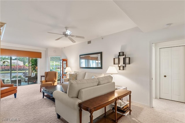 living room featuring baseboards, visible vents, a ceiling fan, and light colored carpet