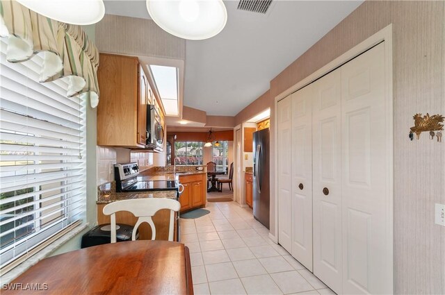 kitchen featuring sink, dark stone countertops, appliances with stainless steel finishes, and light tile patterned floors