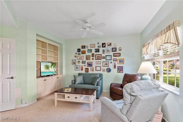 living area featuring baseboards, built in features, a ceiling fan, and light colored carpet