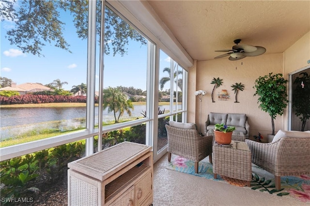 sunroom with ceiling fan and a water view