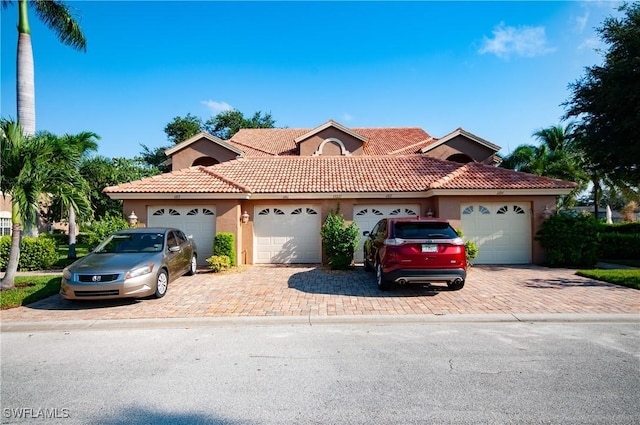 view of front of property featuring decorative driveway, a tiled roof, an attached garage, and stucco siding