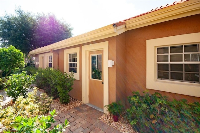 property entrance with a tiled roof and stucco siding