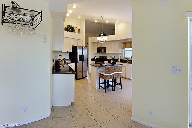 kitchen with white cabinets, dark countertops, a kitchen island, appliances with stainless steel finishes, and a breakfast bar area