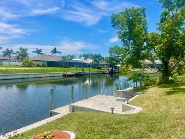 view of dock featuring a lawn and a water view